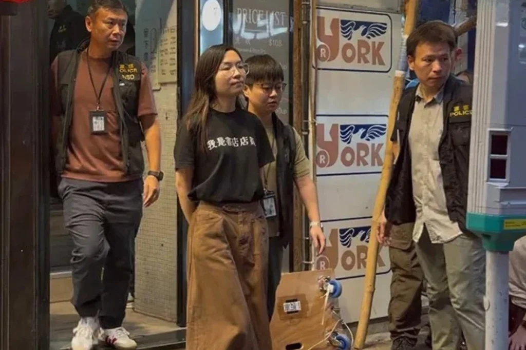 香港國安處搜索留下書舍與田園書屋，一名留下書舍女店員戴著手銬、身穿「我是書店店員」黑色T恤被帶走